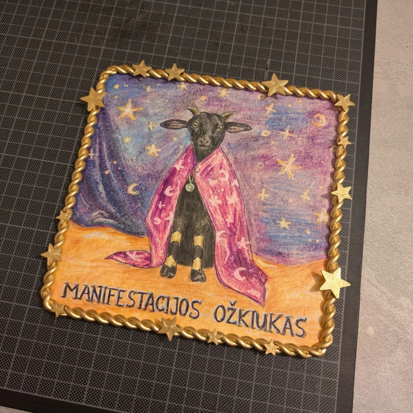 3D spausdintas pynės tipo rėmelis su žvaigždutėmis ir ožiuko piešiniu jame.