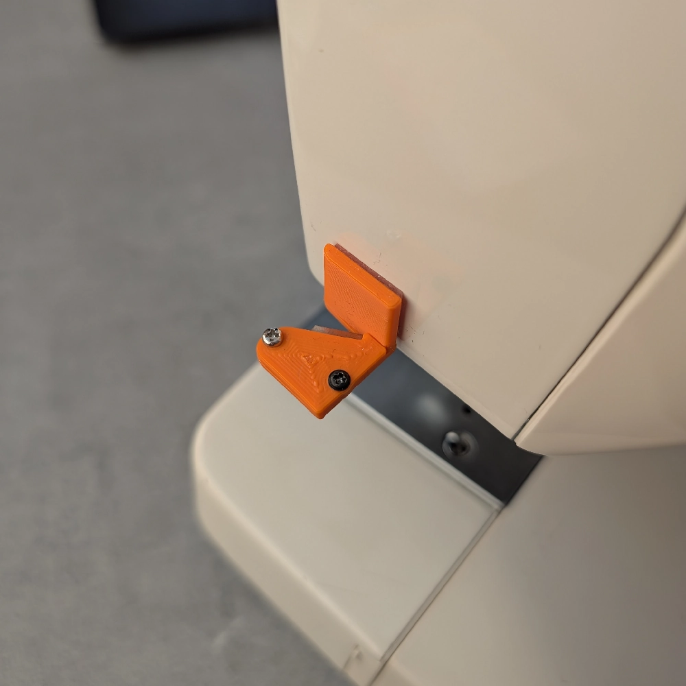 Realus siuvimo mašinos siūlų nupjautukas priklijuotas prie siuvimo mašinos šono.