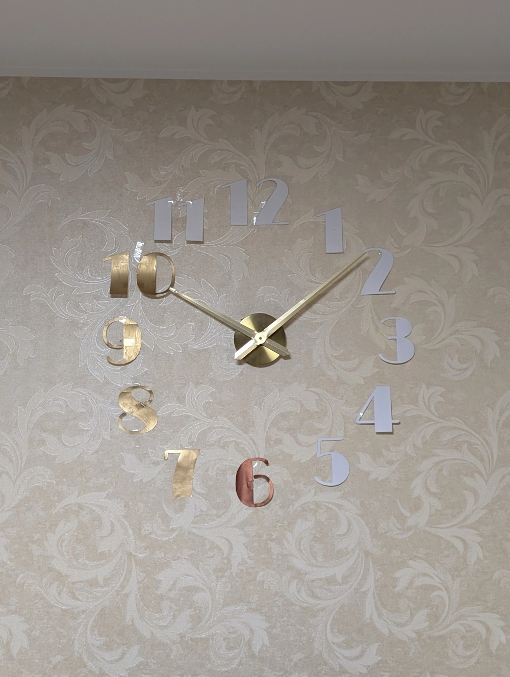 Siena su ant jos pritvirtintomis laikrodžio rodyklėmis ir iškirptais popieriniais skaičiais.