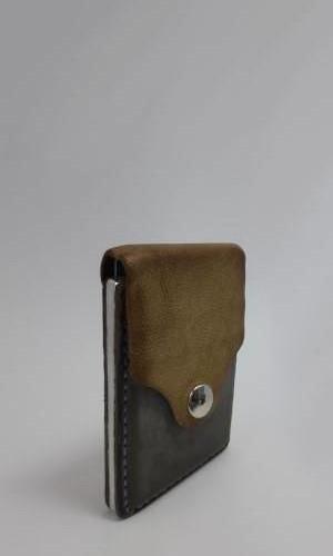 Verikali uždaryta odinė piniginė su aliumininiu rėmeliu monetoms.